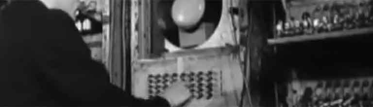 Black and white photograph of a man pressing the keys of an old computer.